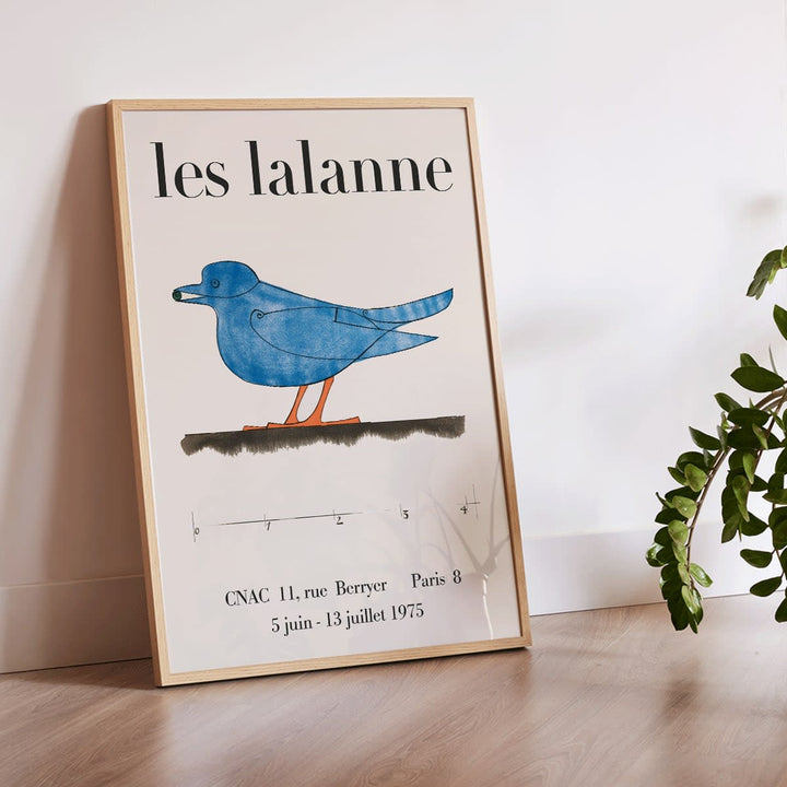 Les Lalanne Exhibition poster by Francois Xavier Lalanne featuring a stylized blue bird with orange legs on beige background, framed and displayed in modern living room decor