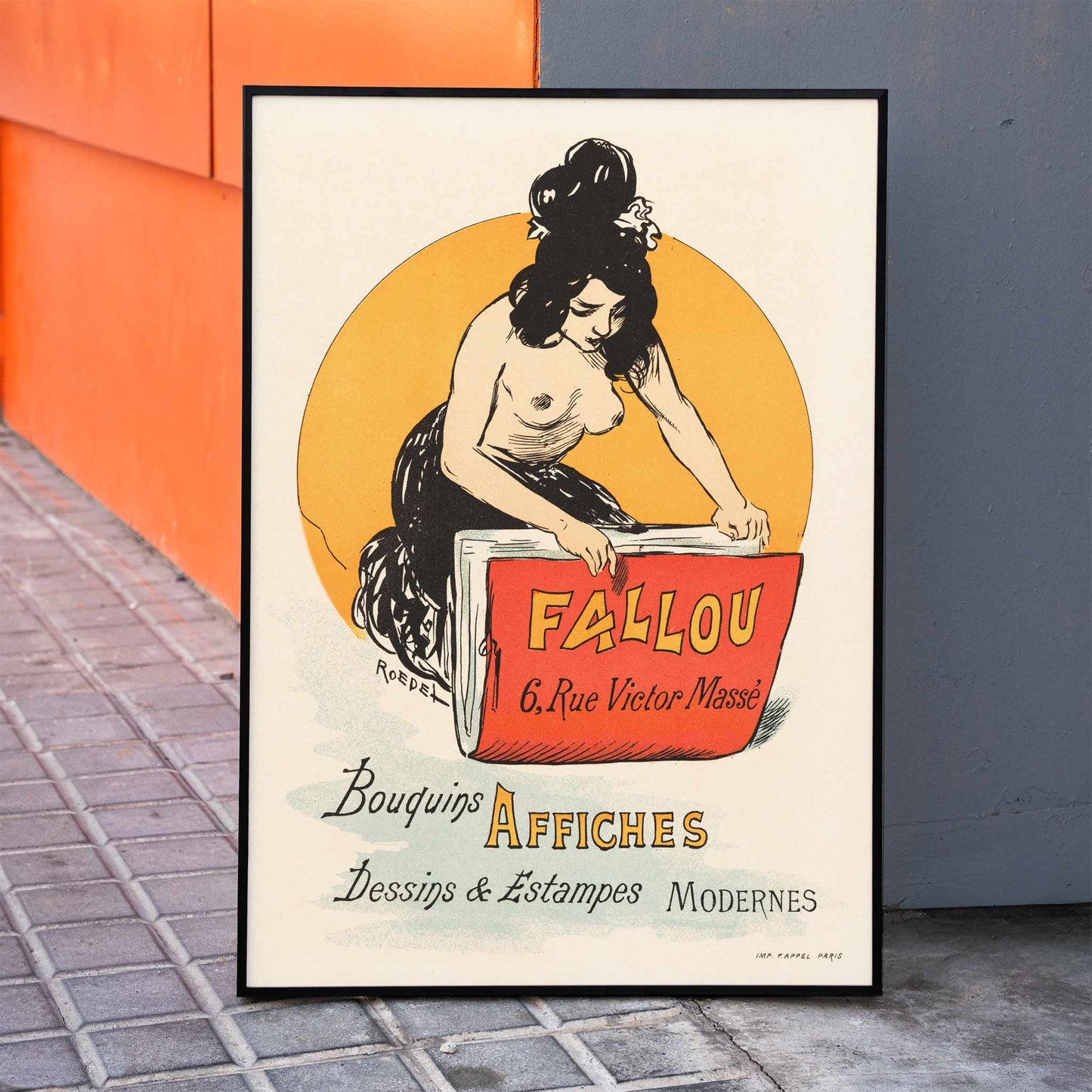 Vintage poster for book and print shop Fallou in Paris by Auguste Roedel featuring a woman with dark hair reading a large red book and holding a colorful book, framed and displayed in home decor