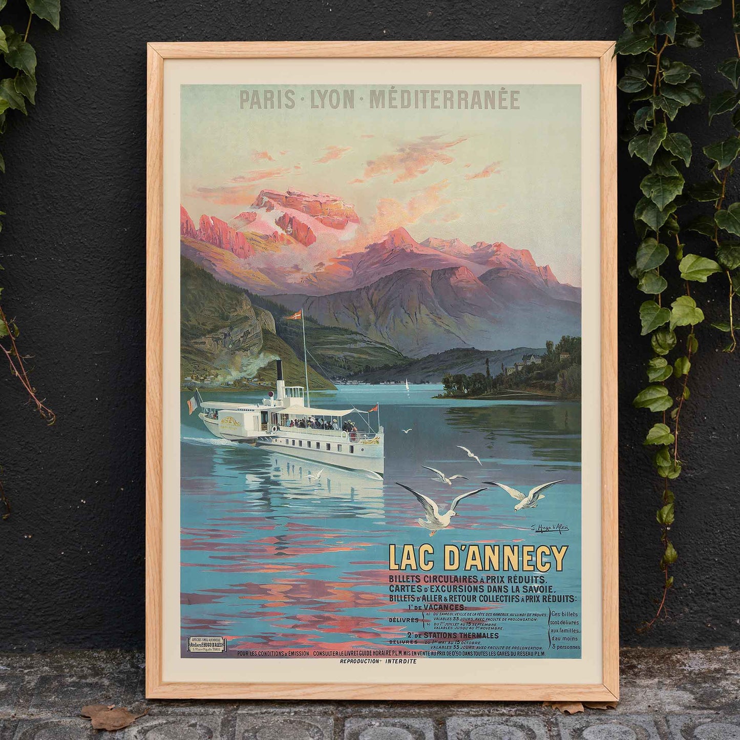 Poster of Le Lac d Annecy by Frederic Hugo d Alesi showing a scenic mountain lake with boat and seagulls at sunset, framed and displayed in home decor