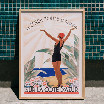 Woman in swimsuit enjoying sunny beach scenery surrounded by flowers Cote dAzur artwork by Roger Broders, framed and displayed in home decor