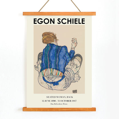 Egon Schiele Woman Seated Back exhibition poster showing a woman in a colorful garment sitting with her back turned artwork, with wooden magnetic frame on white background