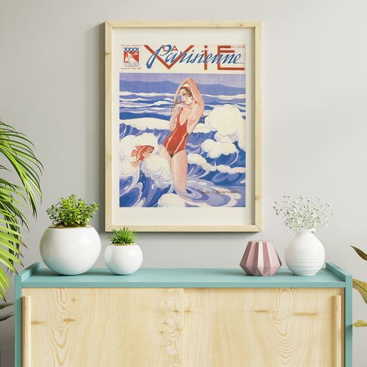 Art Deco poster of La Vie Parisienne by Umberto Brunelleschi showing a woman in a red swimsuit standing in ocean waves with a fish, framed and displayed in home decor